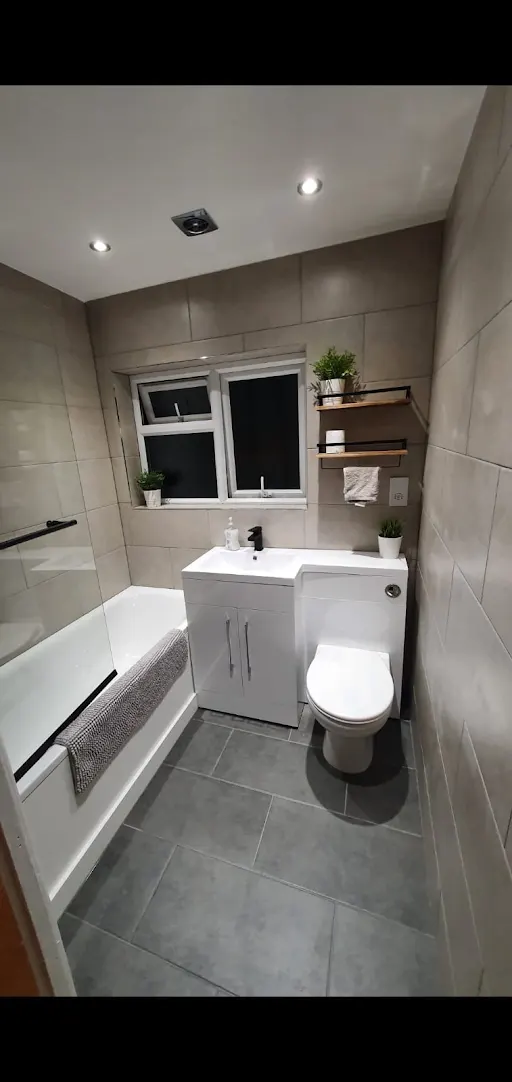 Bathroom installation with grey tiled walls and white vanity unit, Bexley